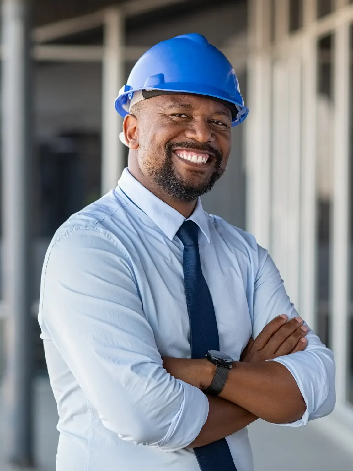 A smiling man in shirt and tie with a hard hat on, representing Reyes Restoration's insurance support
