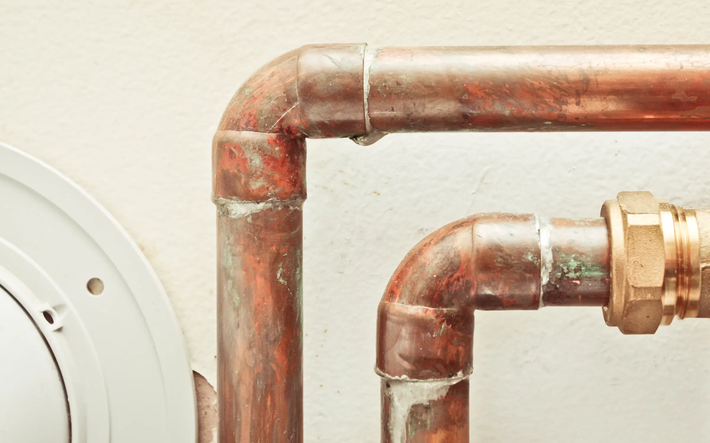 A slowly leaking copper pipe, representing one of the common causes of mold growth that requires remediation