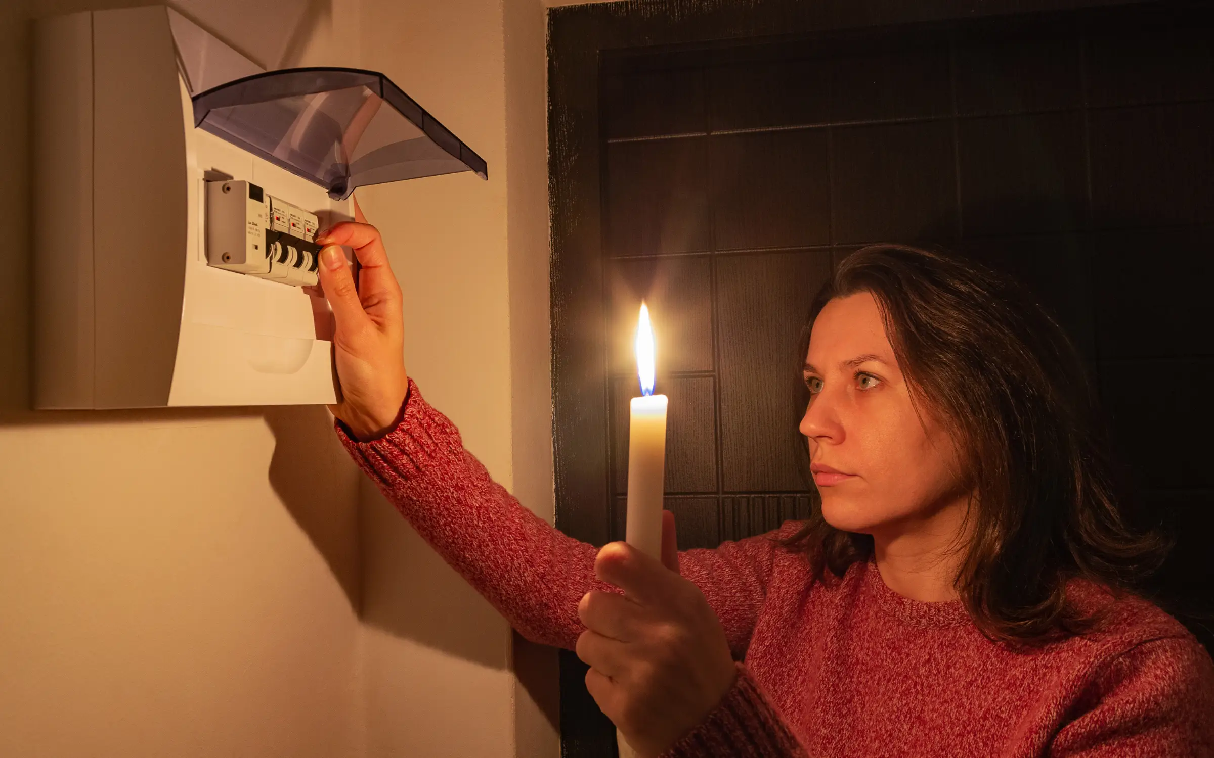 A woman testing her breaker box after a power outage caused by storm damage